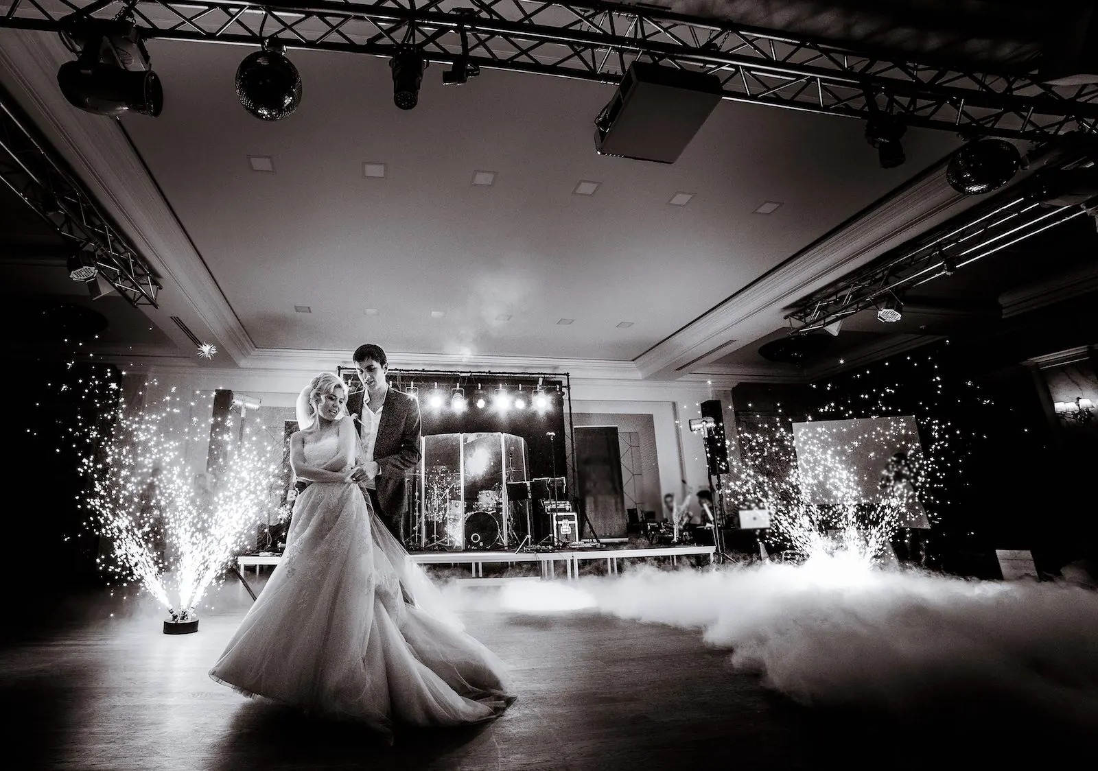 Couple dancing on a cloud of low fog between cold spark fountains
