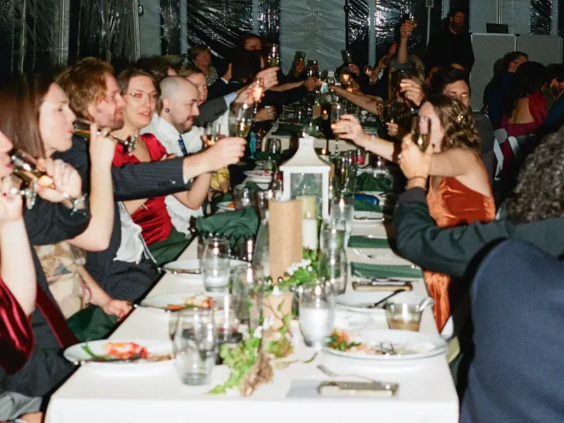 Wedding guests toasting at a long banquet table in a tent